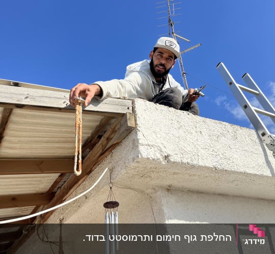 אדם על גג עם אנטנה וסולם לידו